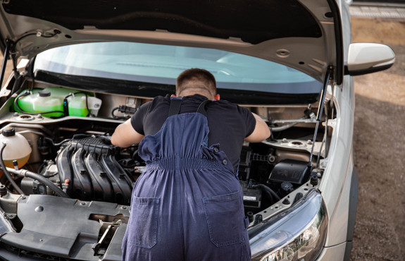 mécanicien travaillant sur moteur automobile capot ouvert 